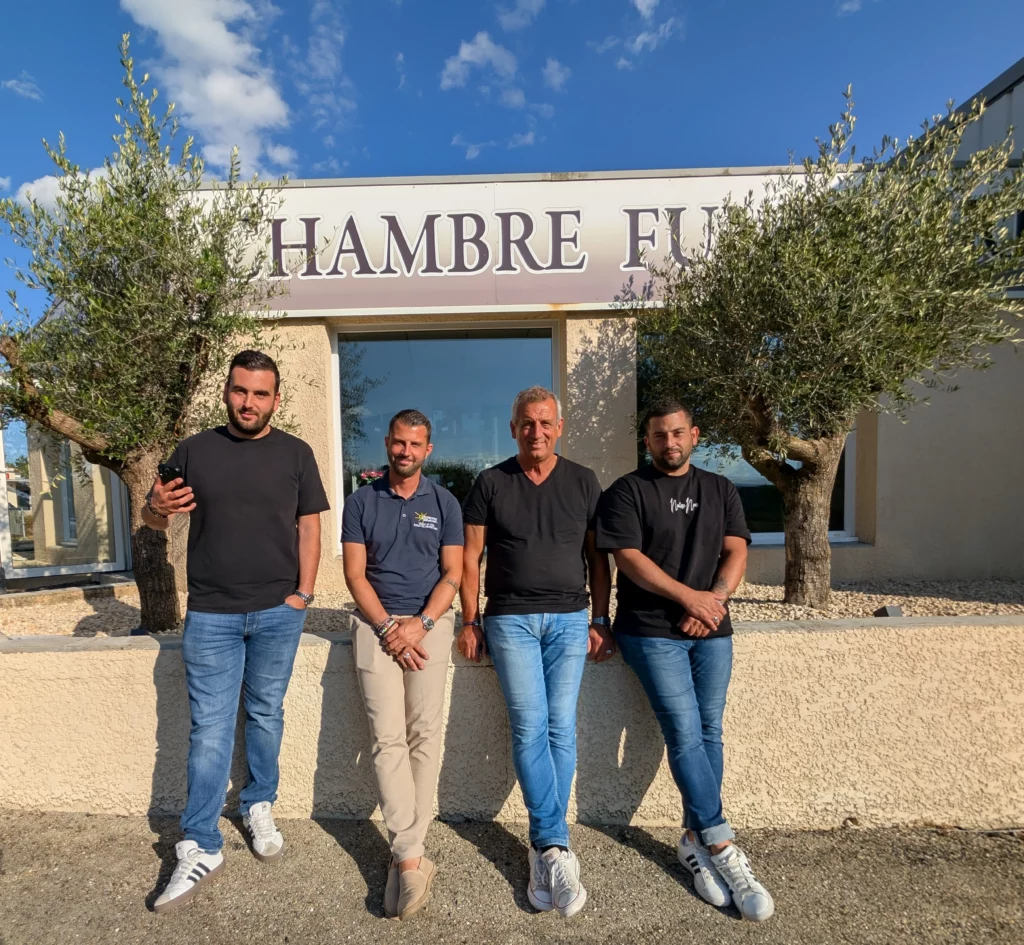 Quatre membres de l'équipe devant le bâtiment de la chambre funéraire.