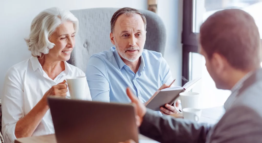 Un couple de seniors en rendez-vous de prévoyance obsèques avec un conseiller.